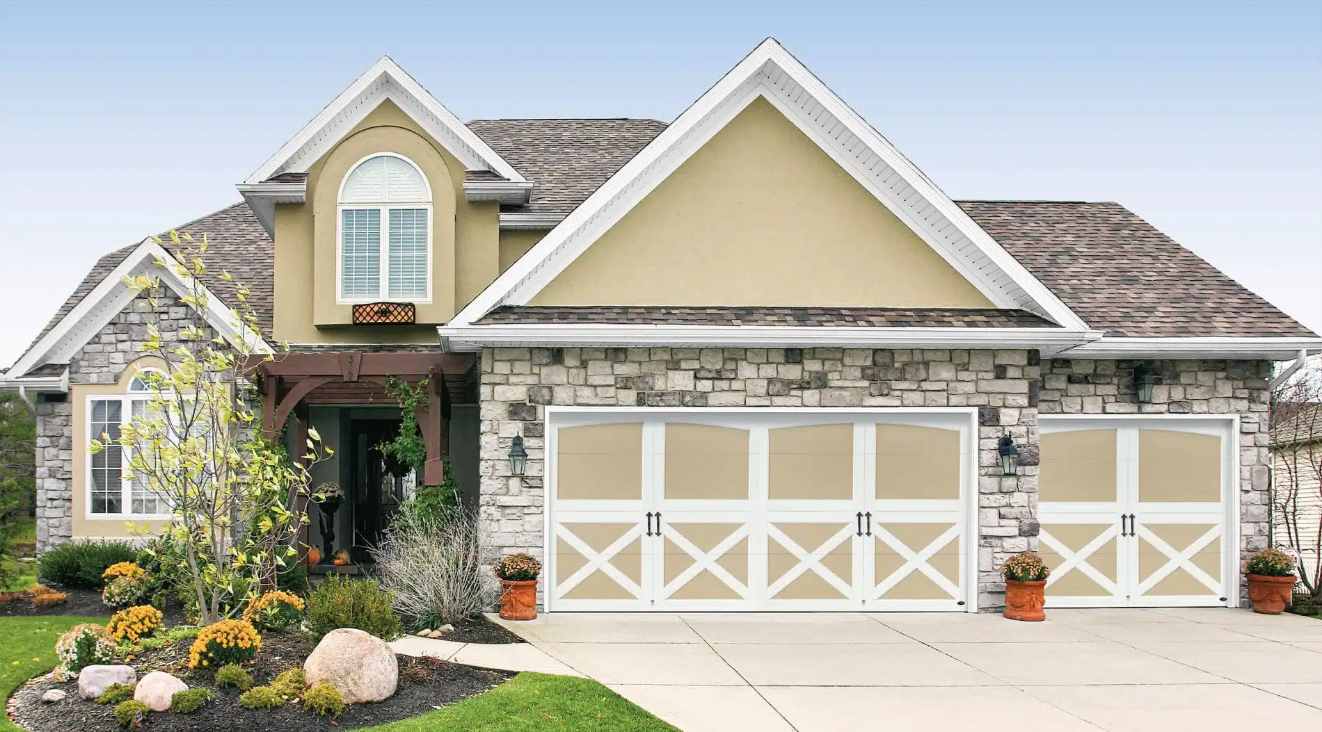 Tanglewood design on 16x7 and 8x7 foot garage doors installed by Garage Service Co on house with stone accents